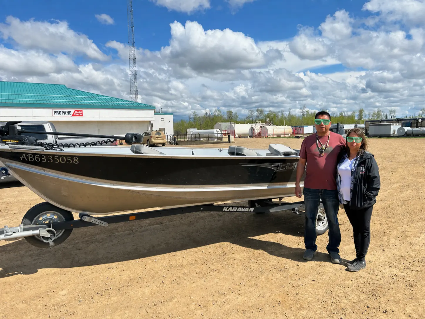 A couple standing in front of their fishing boat on a trailer