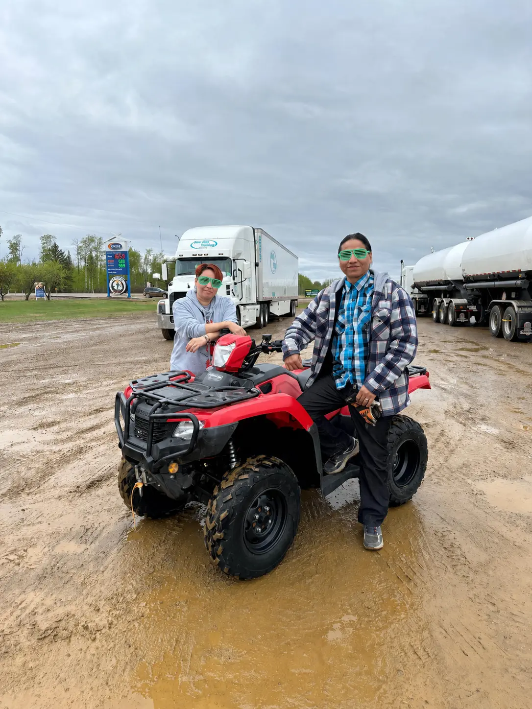 A couple standing with their new red ATV in a field