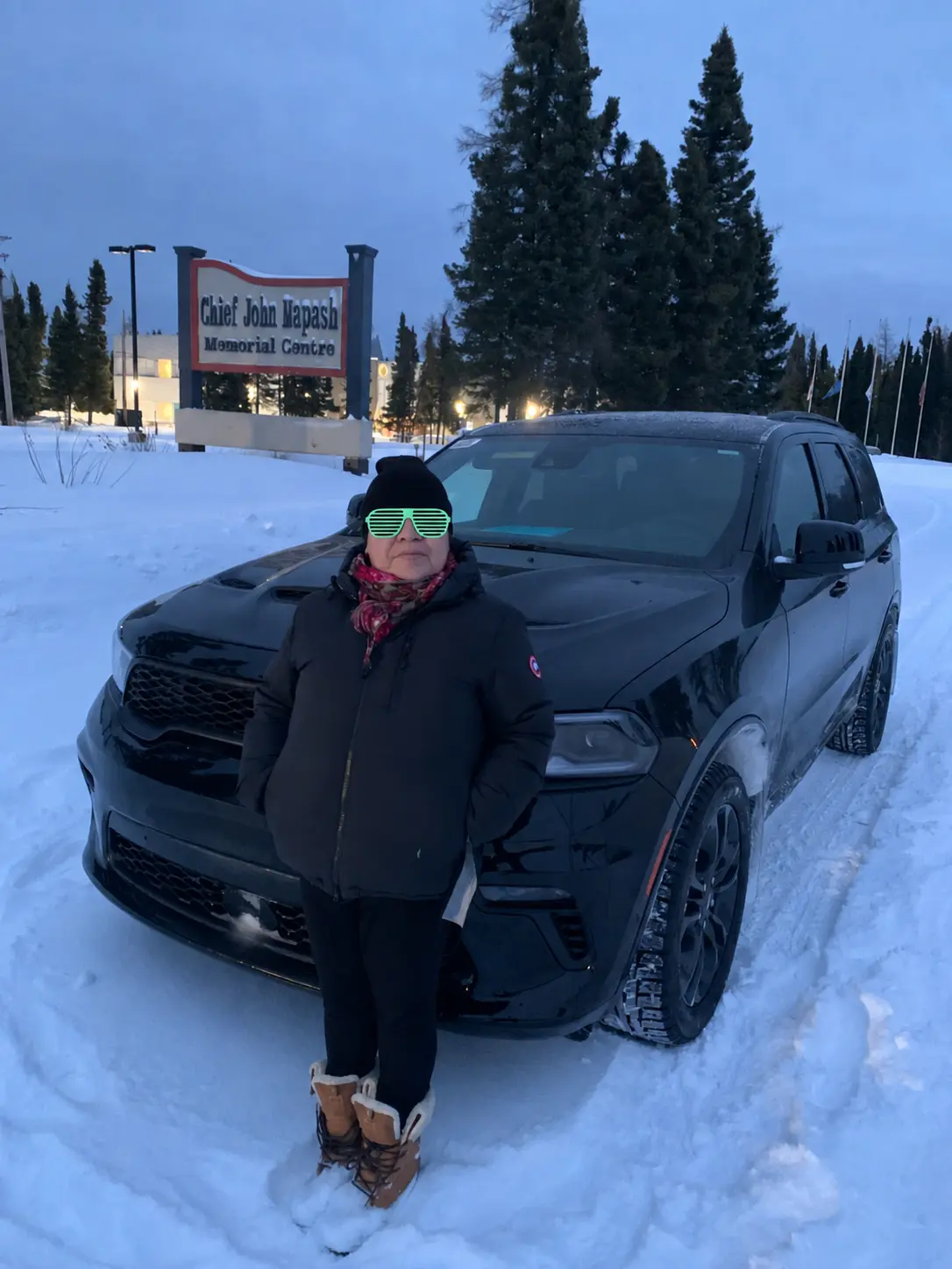 A customer beside a black SUV at a community centre in winter