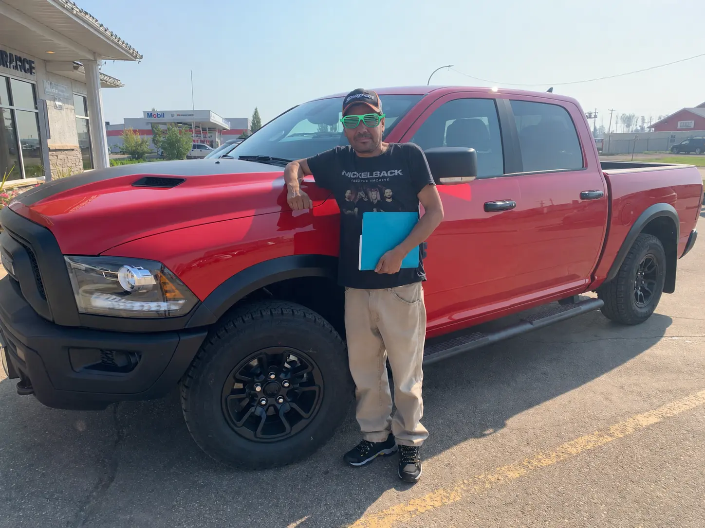 A customer with his paperwork beside a red Ram pickup