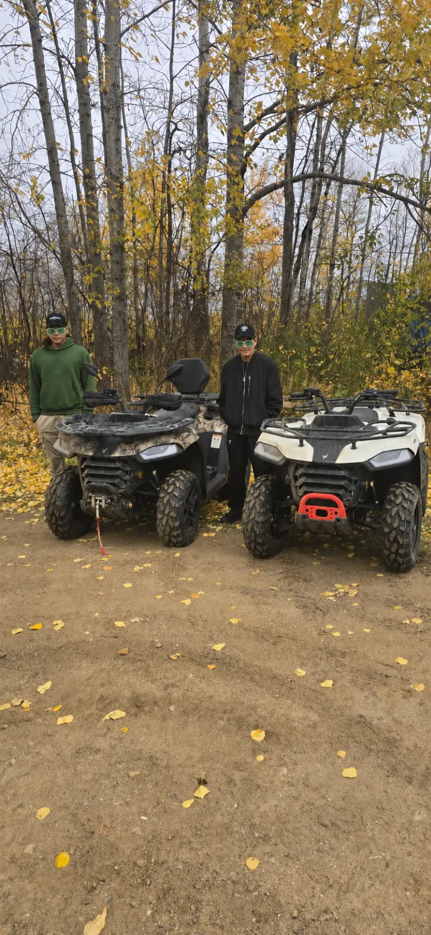Two customers with their ATVs among autumn leaves