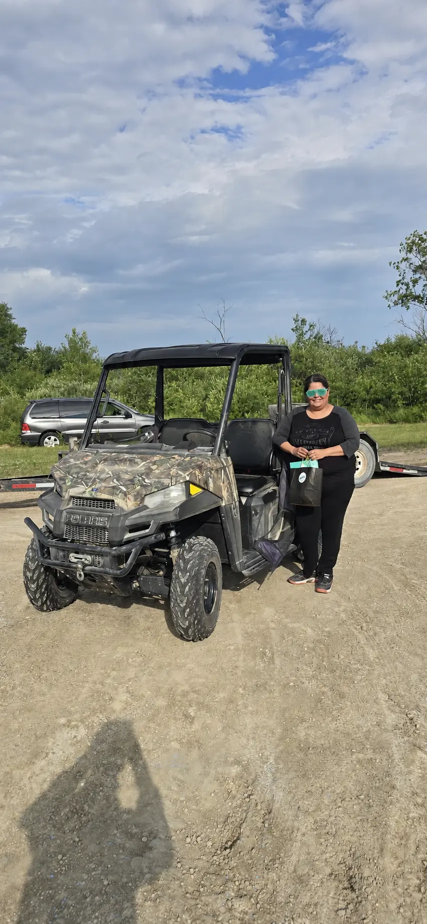 A customer beside her camo Polaris side-by-side